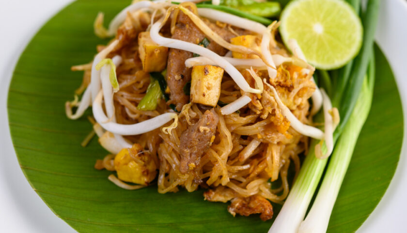 Pad thaï avec des nouilles de riz, des pousses de soja, du poulet, du citron vert et des cacahuètes.